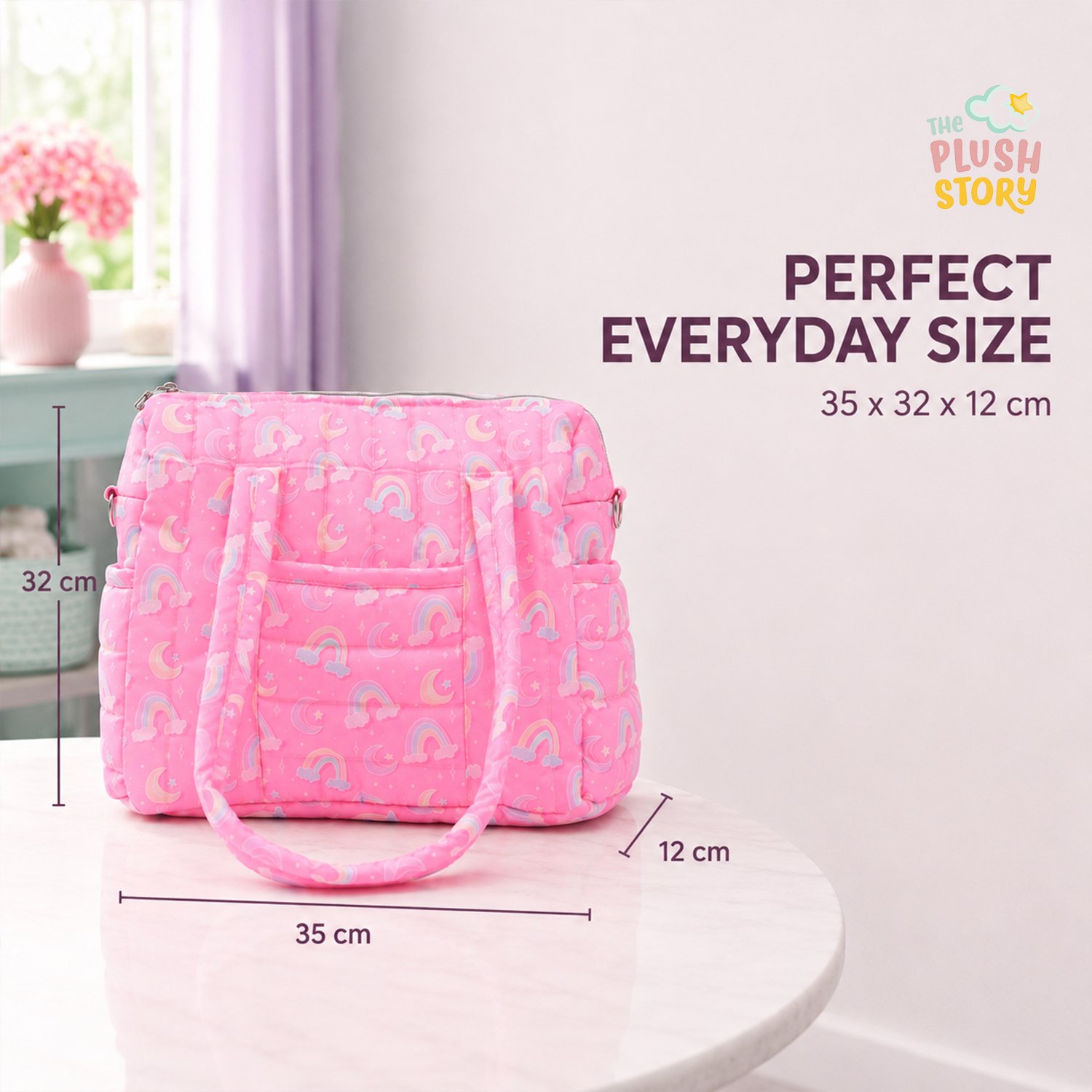 Pink quilted children's bag with rainbow and moon pattern on a white marble table; shows 35×32×12 cm size with 'The Plush Story' logo nearby.