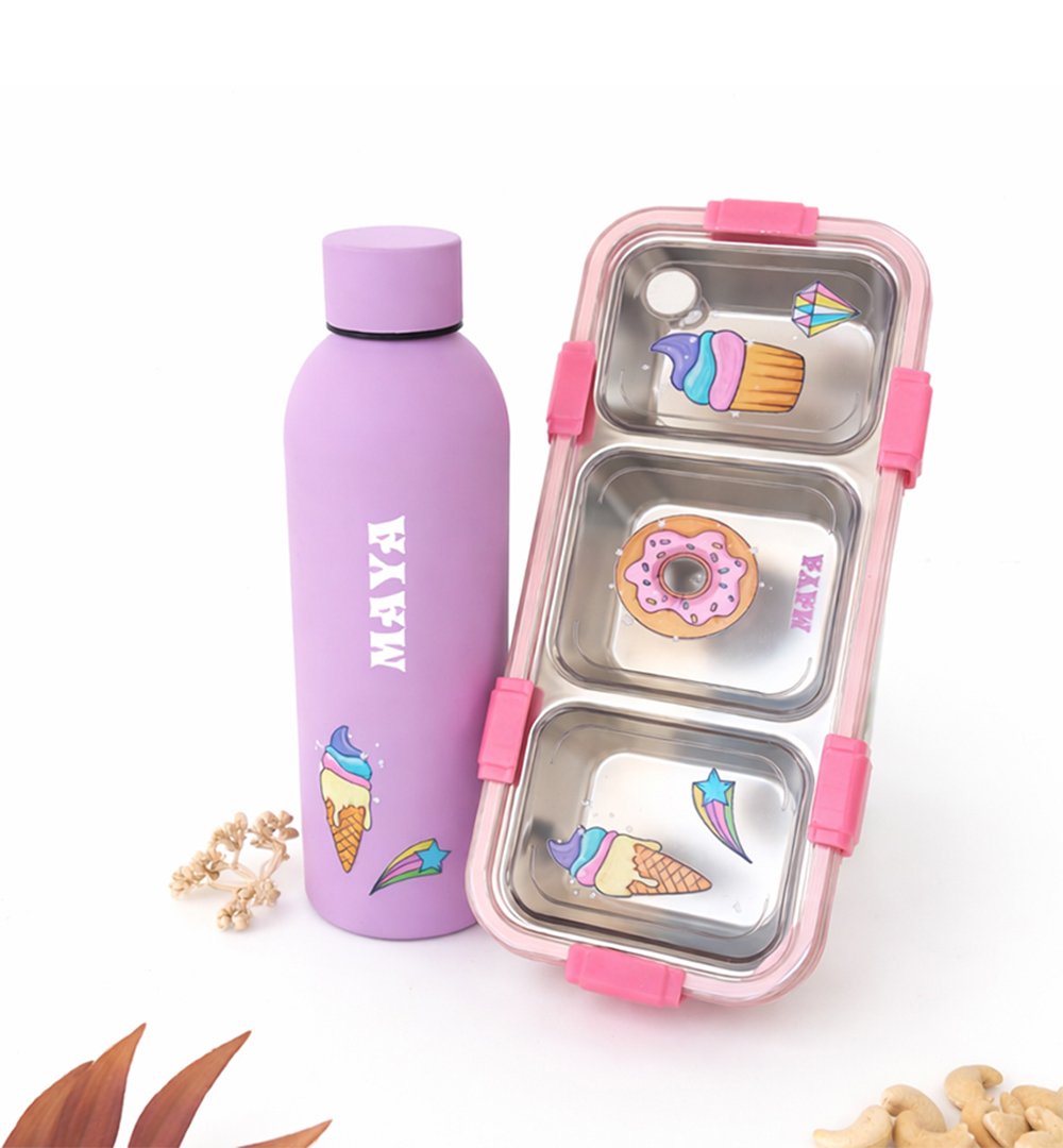 Purple stainless water bottle with ice-cream and donut decals beside a pink-trimmed, three-compartment metal lunchbox with dessert stickers on a white background.