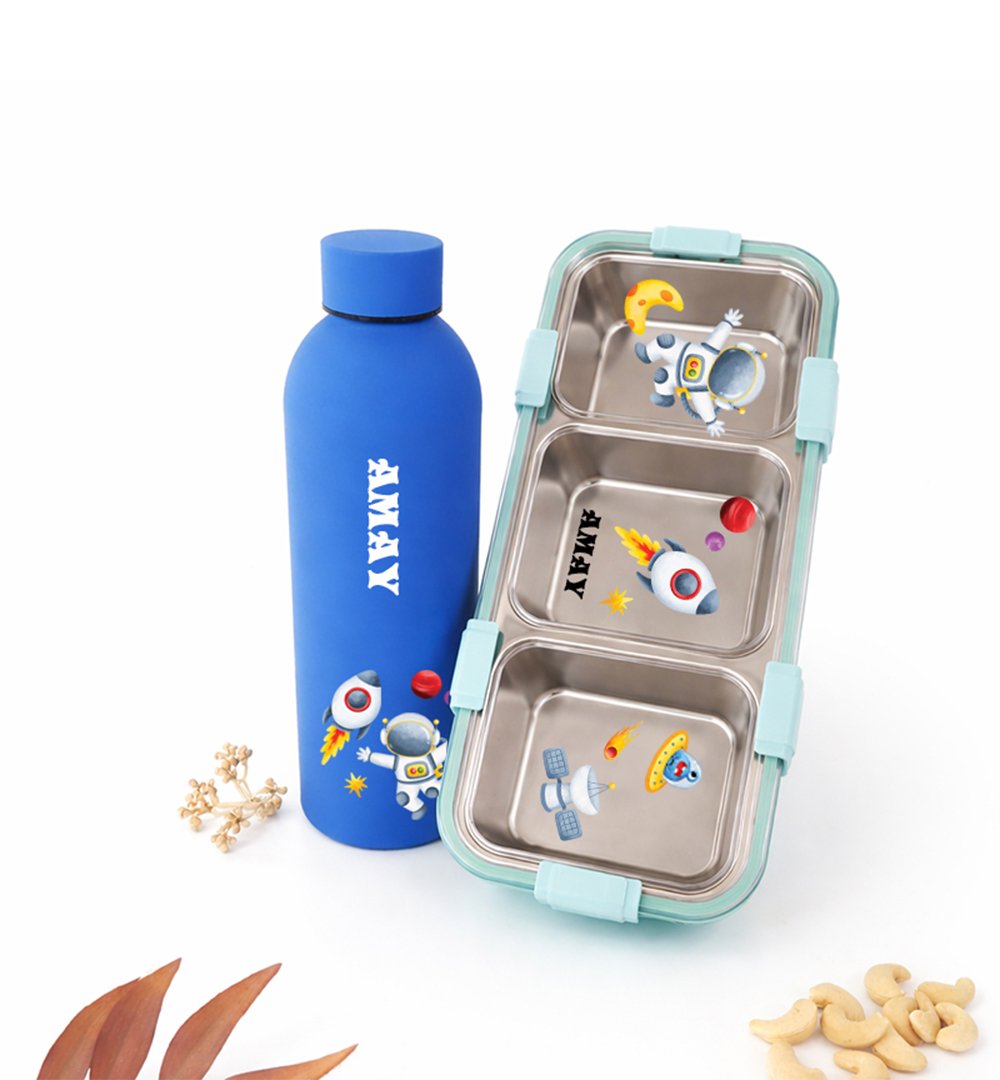 Blue insulated water bottle beside a mint lunchbox with space-themed stickers for kids.