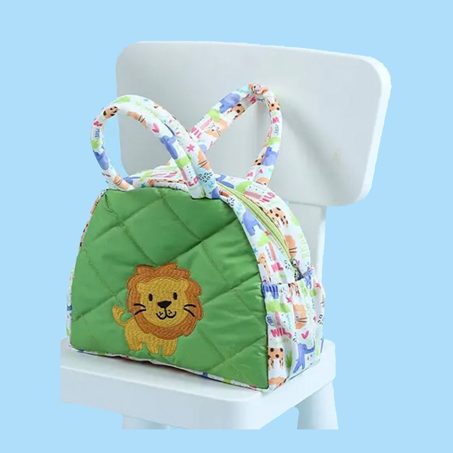 Small green quilted kid's backpack with a lion patch and colorful printed straps, placed on a white chair against a blue background