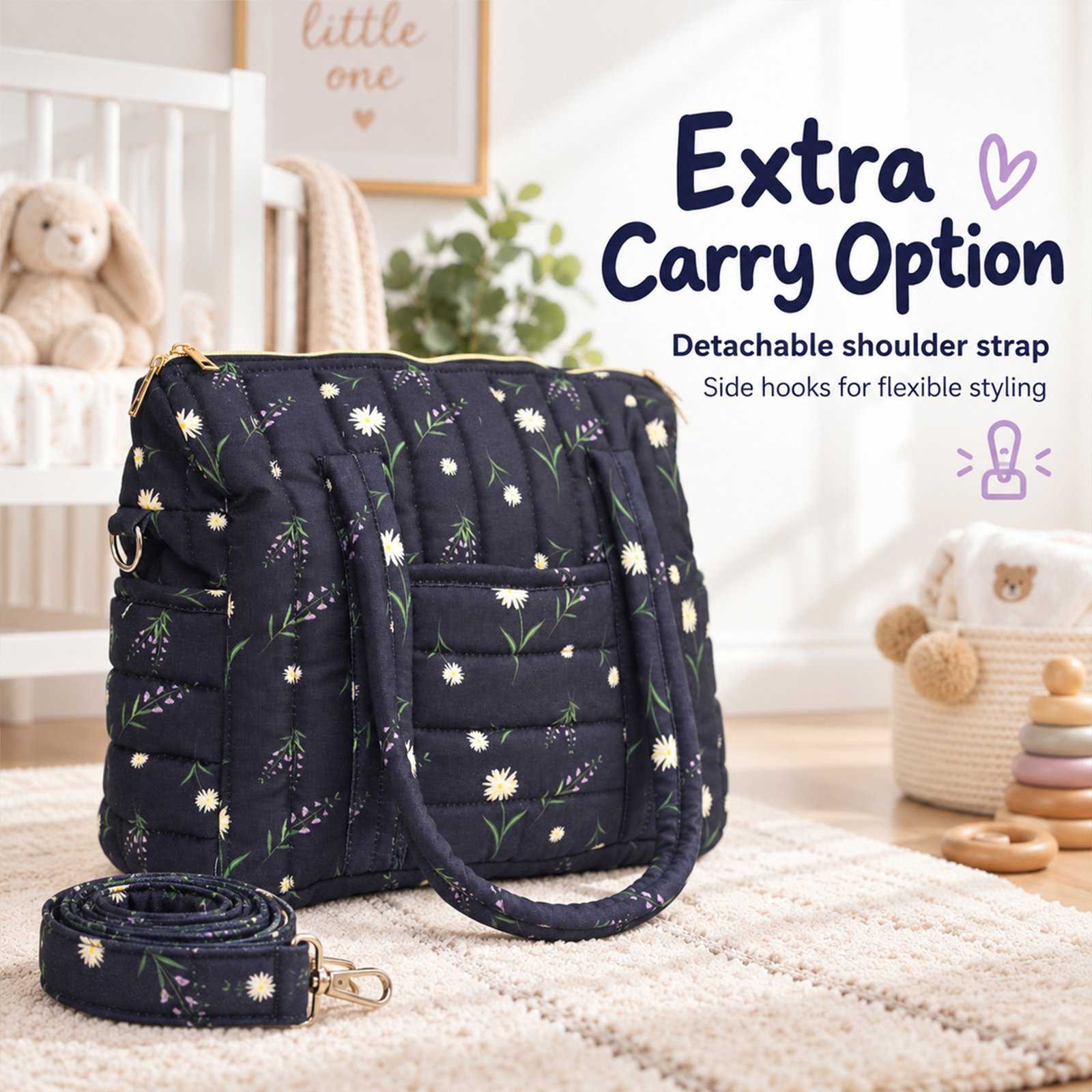 Navy quilted diaper bag with white daisies and a detachable strap on a cream rug in a baby nursery. Behind it, a teddy bear and soft decor are visible in soft focus.