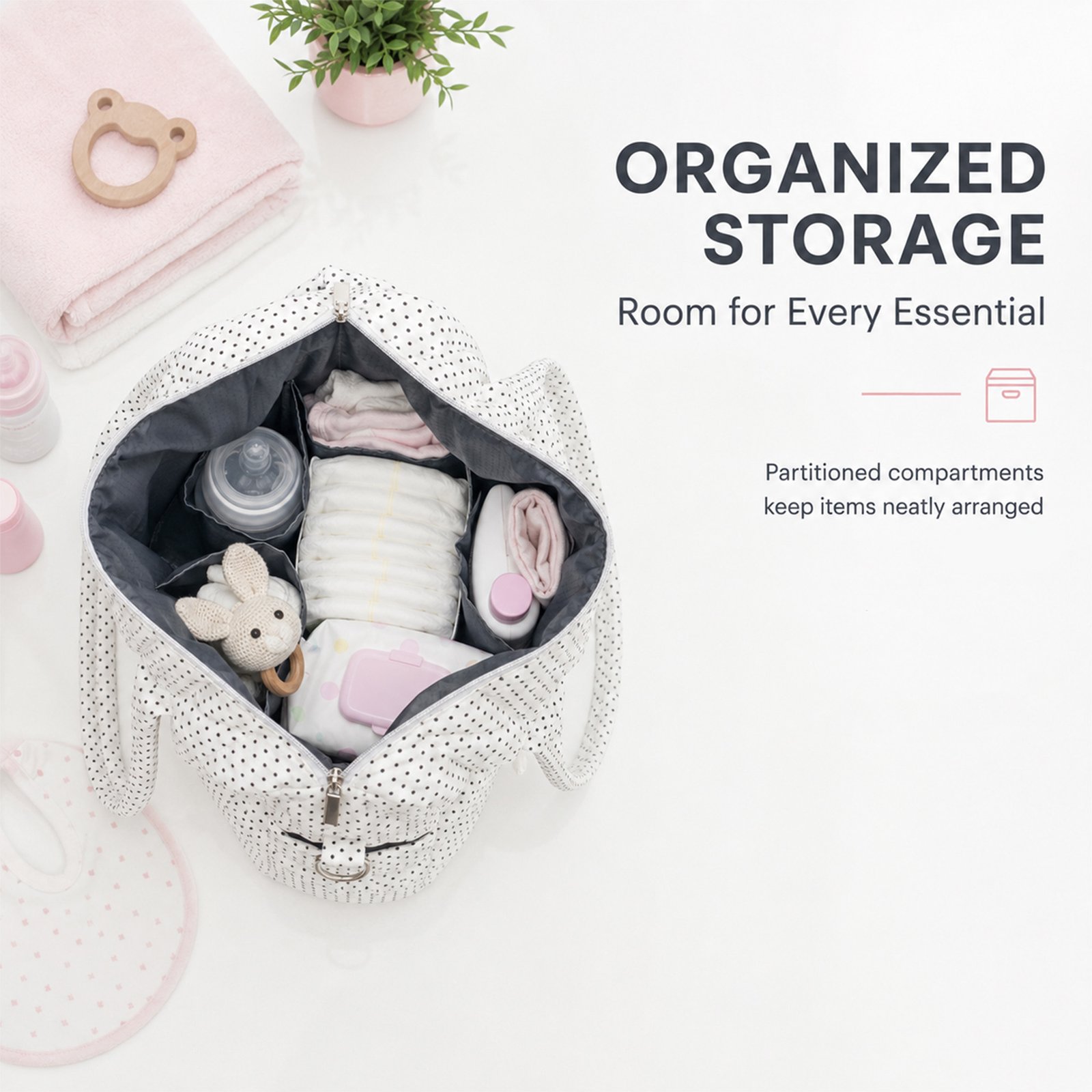 Top-down view of an open dotted bag packed with baby clothes and bottles, surrounded by a pink towel and a small plant near a white surface.