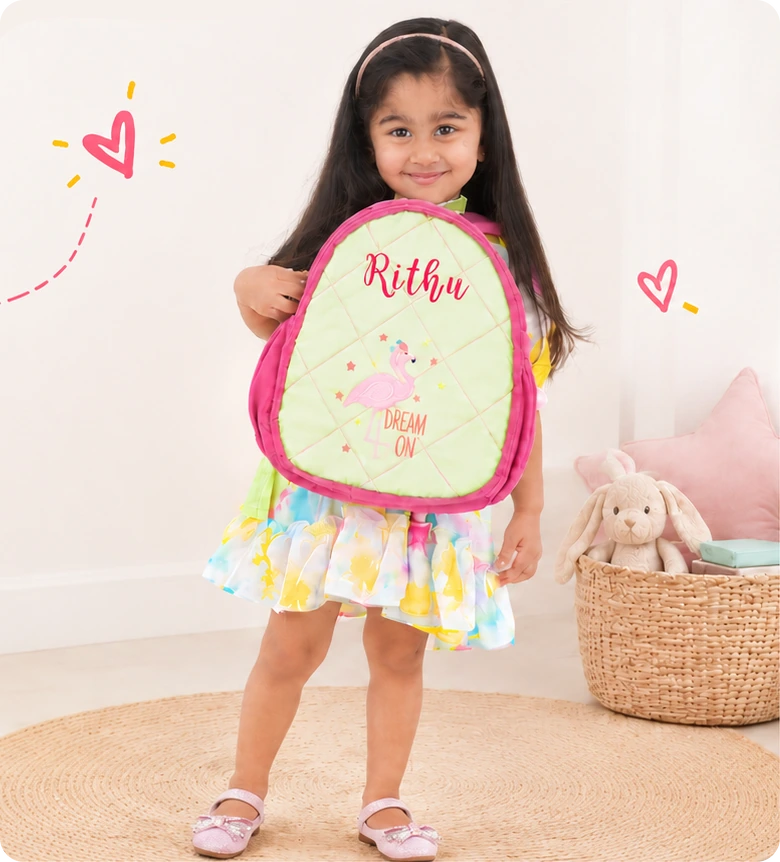 Smiling girl holding a personalised flamingo backpack with her name embroidered on it